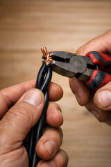 Fototapeta premium Professional electrician hands stripping copper wire with pliers