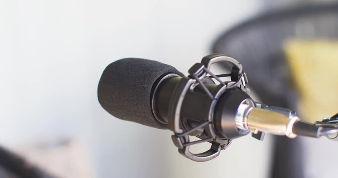 Camera is pulling focus and tightening framing, making foam cardioid mic appear sharper for podcast