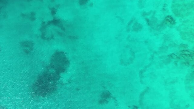 Loopable top down view of turquoise sea in Sardinia showing clear water surface with gentle ripples creating a minimal natural seascape texture