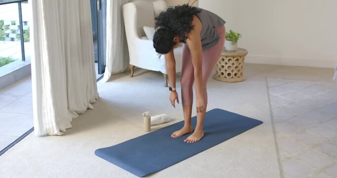 Woman after shifting weight rolling up, raising arms on yoga mat in living room, stretching spine