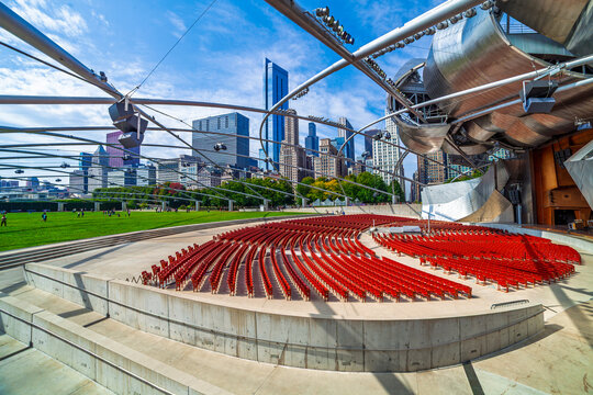 Chicago, IL, USA, September 15, 2024: The Jay Pritzker Pavilion at Millennium Park, featuring Frank Gehry's iconic stainless steel ribbons and overhead trellis against the city skyline.