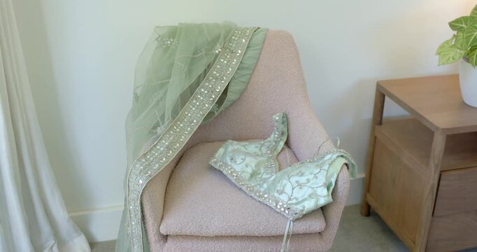 Camera is capturing pink armchair with green embroidered drape and blouse for styling catalog