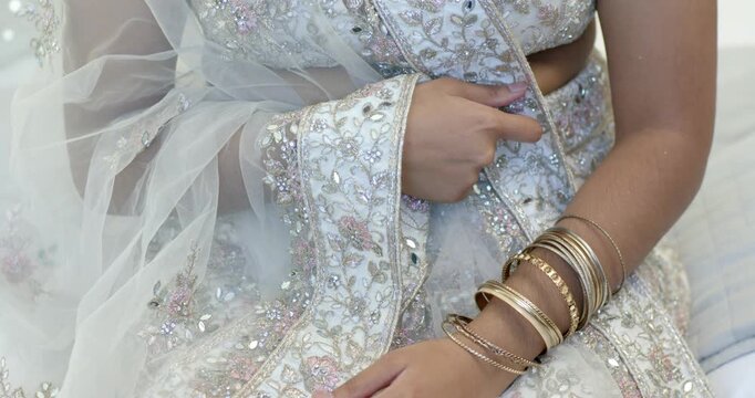 Holding dupatta border, Indian woman smoothing and straightening fabric on sofa, bangles jostling