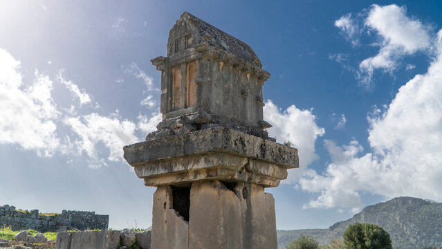 Ancient Lycian pillar tomb at Xanthos ruins in Mugla, Turkey, featuring weathered stone structure and elevated burial monument