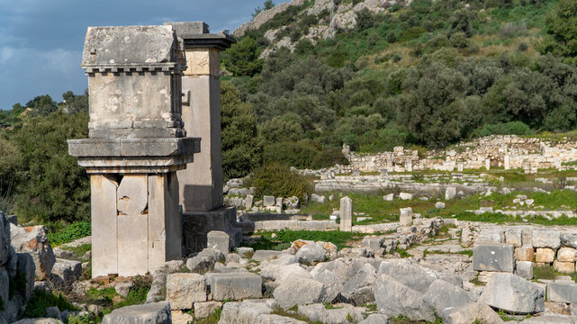 Xanthos archaeological site in Mugla, Turkey, with Lycian pillar tombs, scattered stone ruins and green hillside landscape