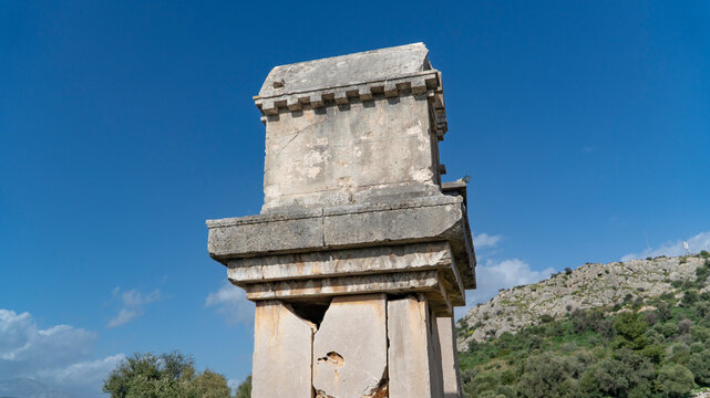 Ancient Lycian pillar tomb at Xanthos ruins in Mugla, Turkey, featuring weathered stone structure and elevated burial monument