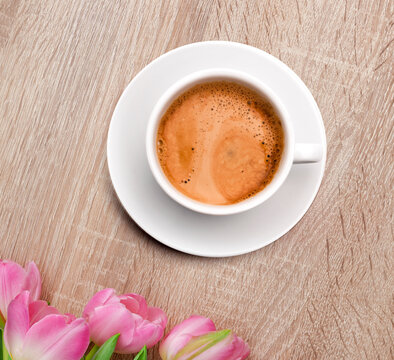 Rosarote Tulpen auf einem hellen Holztisch mit Kaffeetasse