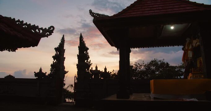 Traditional Balinese temple gate silhouette against a vibrant sunset sky background