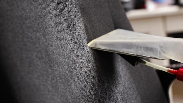 Wet vacuuming a chair to remove dirt and stains in home