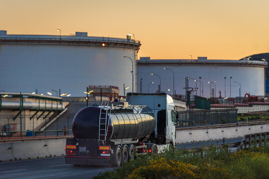 Petroleum tanker truck near large fuel storage tanks refinery setting