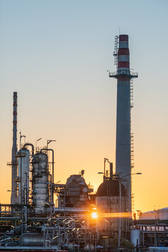 Energy industry refinery detail with pipelines tanks and chimneys at dawn