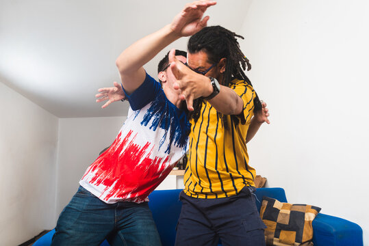 Two friends celebrating a soccer goal with great enthusiasm while watching a game at home during an international sporting event. 