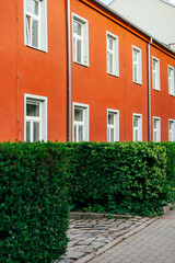 Prostejov, Czech Republic - April 18, 2026: Bright orange residential building facade with white windows and green hedge, ulice Újezd © Professional Art