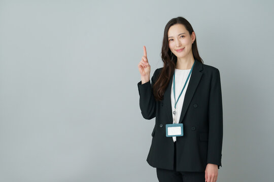 グレーバックの1番のポーズをする若いスーツの日本人女性
