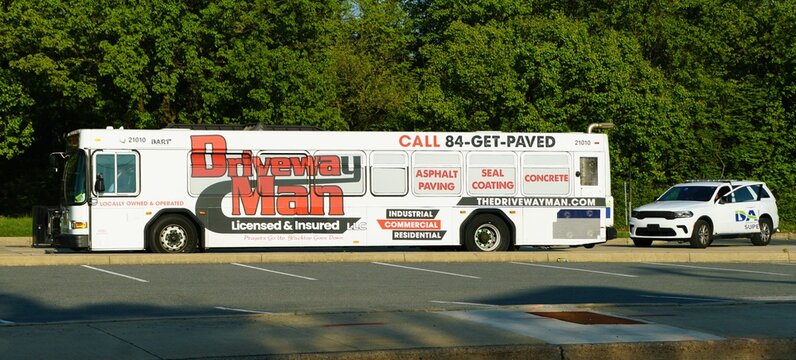 Wilmington, Delaware, U.S - April 23, 2026 - Dart bus wrapped with Driveway Man advertising paving, seal coating, concrete services beside a marked Dart SUV.