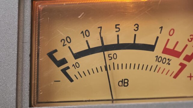 A zoom out reveals two analog VU meters measuring decibels on a classic stereo deck. A warm indicator light glows above the needles to show the vintage equipment in operation.