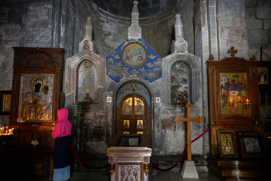 Interior of the ancient Gergeti Trinity Church in Stepantsminda Georgia, spiritual travel experience and cultural heritage concept, person standing before sacred icons in a historic orthodox temple