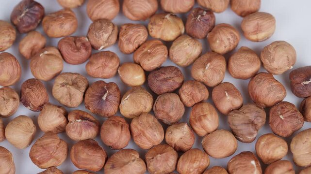 Closeup of crunchy roasted hazelnuts on neutral backdrop. Photograph capturing roasted hazelnut pieces with natural flaws on plain background highlighting warmth and crunch