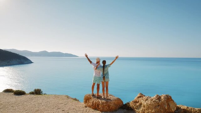 Couple standing on a cliff edge enjoying panoramic sea view in summer Cephalonia