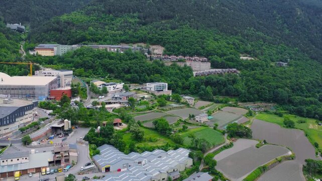 This aerial footage captures the picturesque landscape of Andorra, showcasing the dramatic Pyrenees mountains alongside modern urban development. The drone perspective reveals a mix of lush green fore