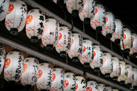 View of traditional Japanese paper lanterns with black calligraphy and red symbols hanging in rows at a shrine, Kyoto, Kyoto, Japan.