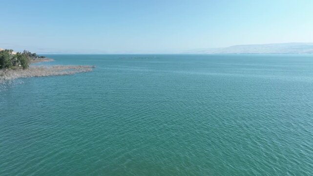 Wide Aerial Panorama of Numerous Jet Skis Cruising Across the Sea of Galilee with Scenic Coastline View