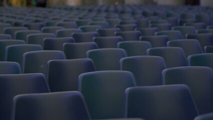 Naklejka premium Wide view of numerous empty blue chairs arranged in symmetrical rows inside spacious hall ready for audience or large scale event