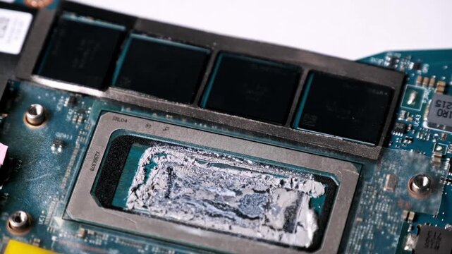 A top-down macro shot displays a computer processor with old dried liquid metal thermal paste. The rotation reveals motherboard circuits representing hardware maintenance.