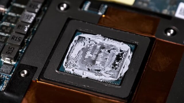 A macro dolly shot captures a graphics processor unit covered in old dried thermal compound. The detailed view of capacitors and copper foil highlights hardware repair concepts.