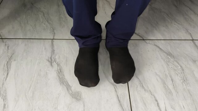 Closeup top view of feets wear uncomfortable and unfit black color casual socks inside living room. Shrunken, cheap, wrong size, too small, mismatch, tight and ill-fitting socks concept.