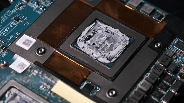 A macro rotating shot reveals a computer CPU with messy thermal paste application. The orbit around the processor highlights motherboard circuits and copper heat dissipation elements.