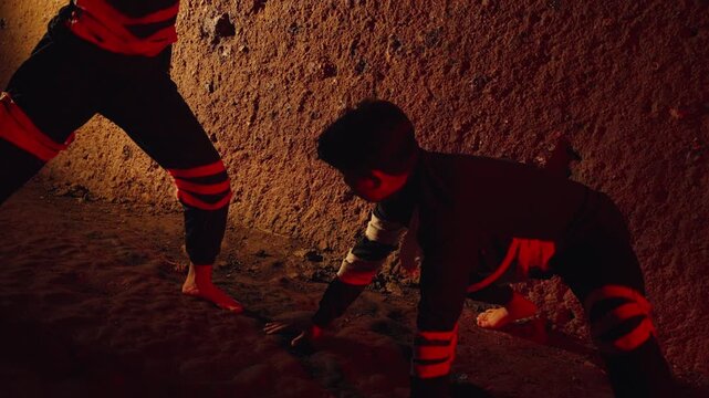 A man and a woman engage in a powerful, confrontational dance inspired by traditional martial arts. Set within a dark, earthy cave, their performance is both a fight and an expressive ritual.