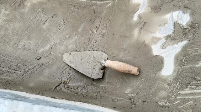 Trowel on wet cement surface during concrete leveling work closeup