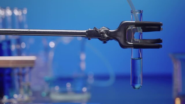 Test tube being filled with blue solution via tubing, static shot 