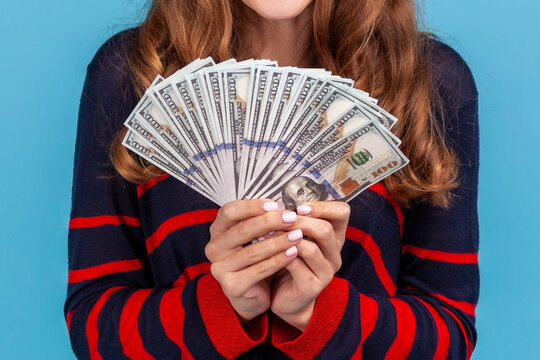Cropped shot of person holding dollar banknotes for lottery winning or financial success and salary bonus isolated over blue background with copy space