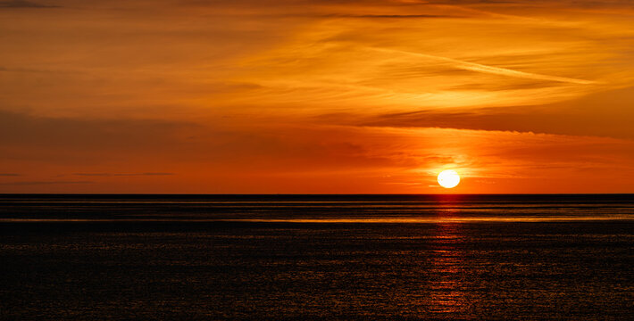 Colorful twilight seascape with orange clouds and calm ocean