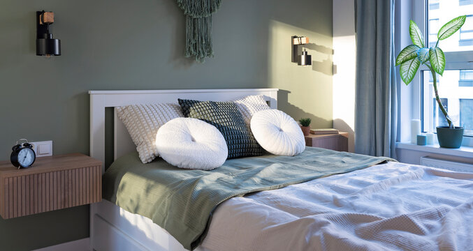 Hotel room with bed in boho style. Cozy bedroom with window and light and green wall in stylish interior. Panoramic.