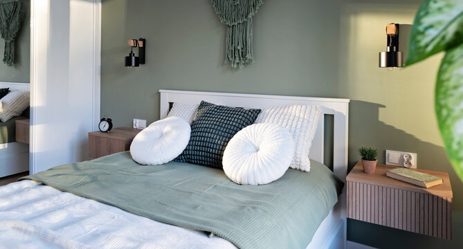 Modern living room with bed, white pillow and green wall in boho interior. Room at home with stylish design. Real estate. Panoramic.