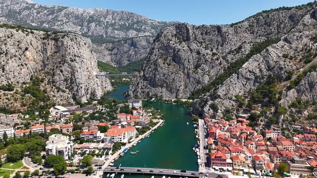 Aerial view of Omis town and Cetina river canyon in Croatia, scenic landscape with mountains and red roof houses.