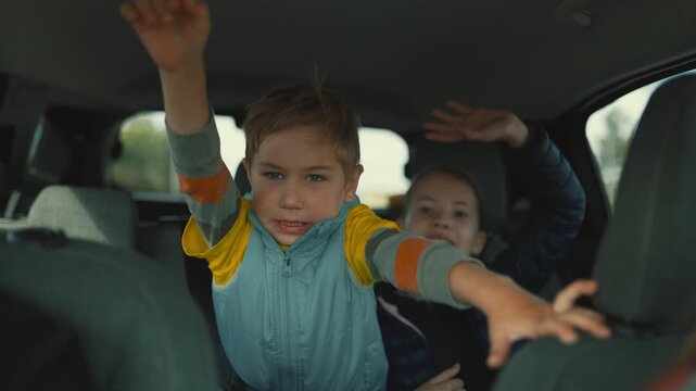 Playful boy and girl making funny faces in car backseat
