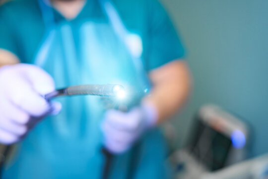 Adult person holding medical endoscope in examination room