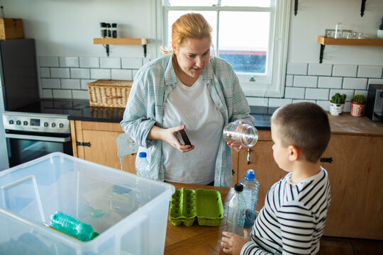 Mother teaching son recycling in home kitchen