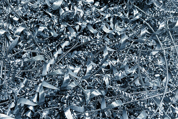 Shiny metal shavings and curled steel swarf background from machining process. Industrial manufacturing waste concept. Silver metallic scrap closeup. Engineering production material backdrop. © Paweł Michałowski