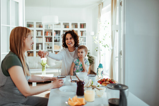 Mother and child greeting friend at home dining table