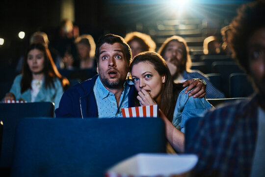 Nervous couple watching thriller in movie theater