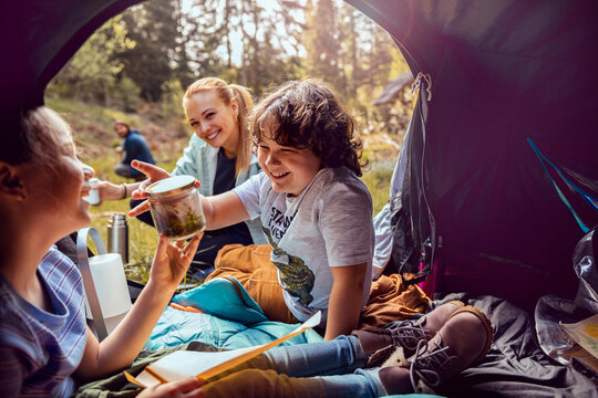 Family camping with children studying nature inside a forest tent