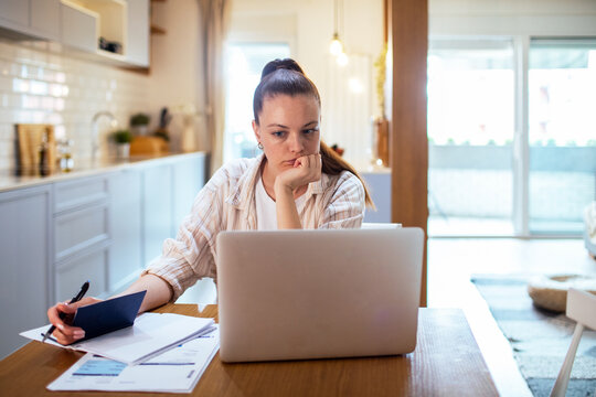 Young woman budgeting with laptop at home kitchen table