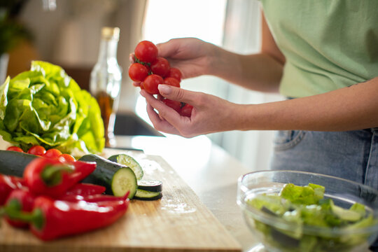 Woman preparing fresh salad in home kitchen