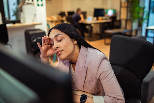 Tired businesswoman rubbing eyes at computer in office