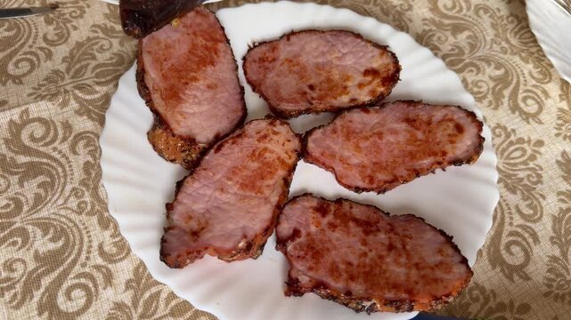 Fried pork steaks on plate, golden edges and crispy crust, arranged on white scalloped plate over patterned tablecloth, rustic